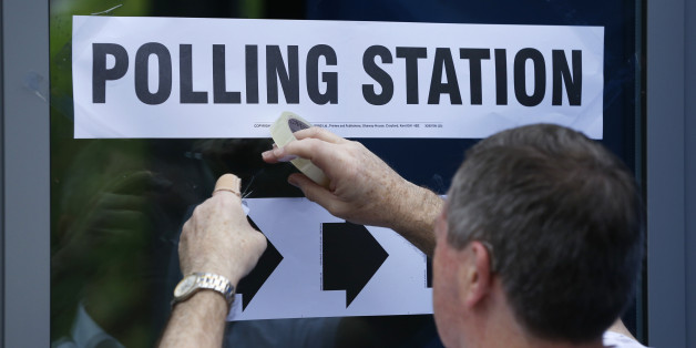 A man puts up a sign at a polling station for the Referendum on the European Union in Heald Green, Stockport, Britain, June 23, 2016. REUTERS/Andrew Yates