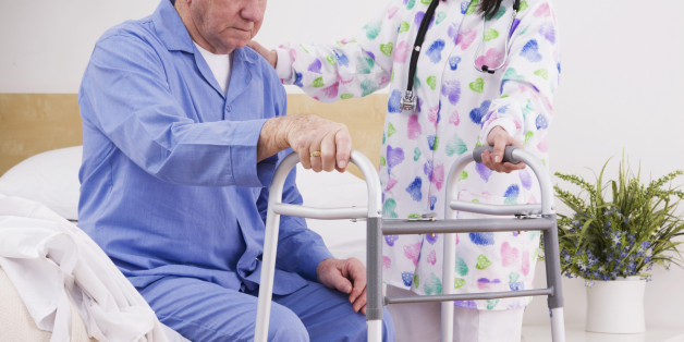 Female nurse assisting senior man with walking frame