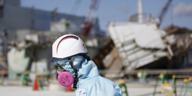 FILE - In this Feb. 10, 2016, file photo, a Tokyo Electric Power Co. (TEPCO) employee, wearing a protective suit and a mask, walks in front of the No. 1 reactor building at the tsunami-crippled Fukushima Dai-ichi nuclear power plant in Okuma, Fukushima Prefecture, northeastern Japan. Five years after a powerful earthquake and tsunami sent the nuclear power plant in the country into multiple meltdowns, cleaning up the mess both onsite and in surrounding towns remains a work in progress. (Toru Hanai/Pool Photo via AP, File)