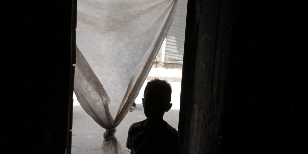 In this Monday, May 16, 2016 photo, A Syrian refugee child leaves a commercial space that a family has rented to live in, in the city of Gaziantep, southeastern Turkey. The family is one of thousands of refugees living in Turkey using a debit card, provided by the World Food Program, to partially take care of their groceries. Turkey, host to the largest refugee population in the world, including 2.7 million Syrians, is on the front line of the crisis. (AP Photo/Lefteris Pitarakis)