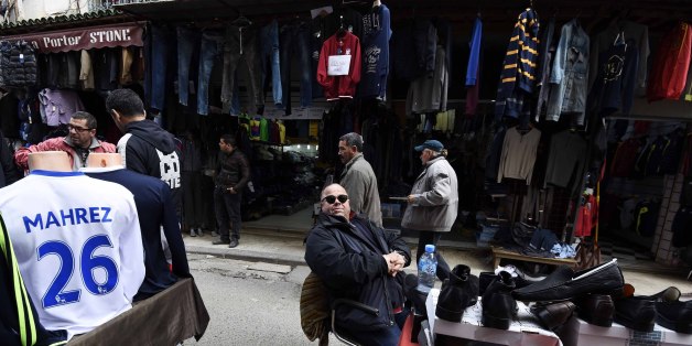 An Algerian vendor sits next to a shirt of English football club Leicester City's midfielder Riyad Mahrez displayed at a market on February 18, 2016 in the old part of the capital Algiers, known as the Casbah. Riyad Mahrez shirts are flying off the shelves of sports shops in Algiers as the Algerian winger continues to impress for Premier League leaders Leicester City. / AFP / Farouk Batiche (Photo credit should read FAROUK BATICHE/AFP/Getty Images)