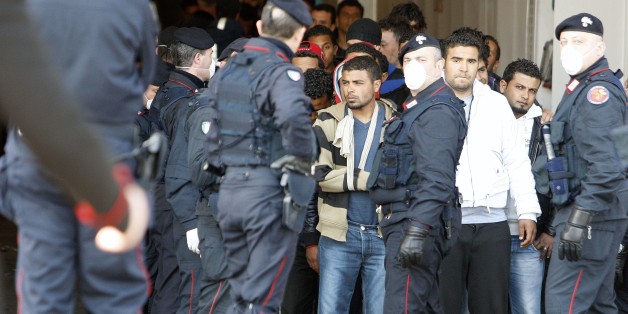 Policemen guard as Tunisian would-be immigrants disembark from a ferry boat during their evacuation from the Italian island of Lampedusa to a reception centre in Manduria in the Puglia region, run after escaping from the camp on April 1, 2011. The Italian government has prepared a plan to accommodate 10,000 migrants on a temporary basis, before repatriating them to Tunisia. AFP PHOTO / CARLO HERMAN (Photo credit should read CARLO HERMANN/AFP/Getty Images)