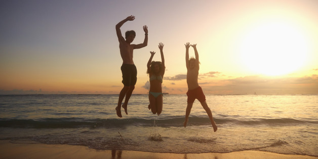 Caucasian children jumping for joy on beach