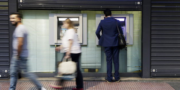 A customer operates an automated teller machine (ATM) beneath metal shutters in Athens, Greece, on Thursday, July 16, 2015. Germany's Parliament is set to ratify bridge financing and the start of talks for a three-year rescue plan. Photographer: Matthew Lloyd/Bloomberg via Getty Images