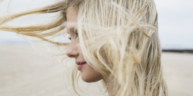 Wind blowing blonde hair of woman at beach
