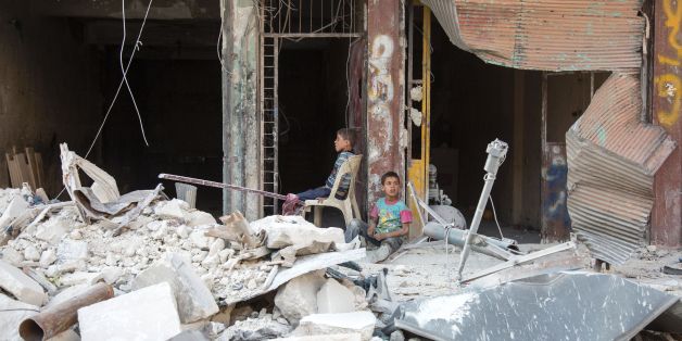 Syrian children sit amidst the rubble of destroyed buildings on July 6, 2016 in the rebel-held district of Tariq al-Bab of the northern city of Aleppo.The Syrian army said it was observing a 72-hour ceasefire across the country coinciding with the festival marking the end of the Islamic holy month of Ramadan. As fighting continued on the ground, especially in second city Aleppo, some rebel groups said they would respect the ceasefire although they doubted the seriousness of the regime of Preside
