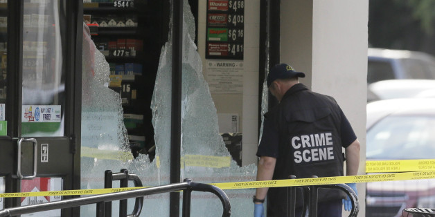 A crime scene investigator looks a shot out windows after a shooting in downtown Dallas, Friday, July 8, 2016. Snipers opened fire on police officers in the heart of Dallas during protests over two recent fatal police shootings of black men. (AP Photo/LM Otero)