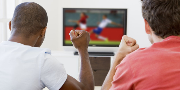 Two men in living room watching television and cheering