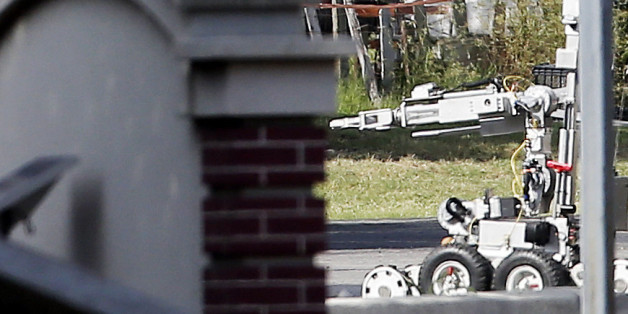 A bomb disposal robot inspects the area surrounding a armored van, top left of frame, near the intersection of Dowdy Ferry Rd and Interstate 45 during a stand off with a gunman barricaded inside the van, Saturday, June 13, 2015, in Hutchins, Texas. The gunman allegedly attacked Dallas Police Headquarters. (AP Photo/Brandon Wade)