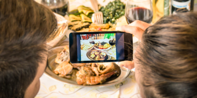 Couple of boyfriend and girlfriend taking a food selfie in dinner restaurant - Moda of catching the instant with modern smartphone at lunch meeting with typical italian food