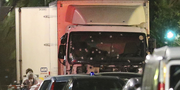 A policeman stands, watching the truck used for the attack near the scene of an attack after a truck drove onto the sidewalk late Thursday, and plowed through a crowd of revelers who gathered to watch the fireworks in the French resort city of Nice, southern France, Friday, July 15, 2016. (AP Photo/Luca Bruno)