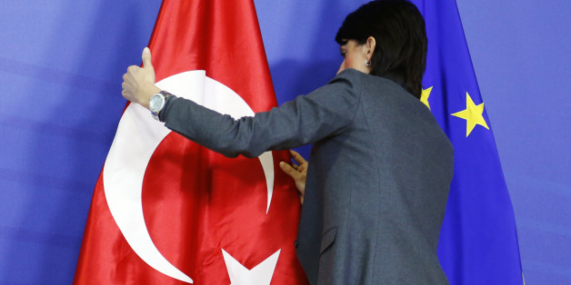 A staff adjusts European Union and Turkish (L) flags ahead of the arrival of Turkey's Prime Minister Tayyip Erdogan (not pictured) at the EU Commission headquarters in Brussels January 21, 2014. REUTERS/Francois Lenoir (BELGIUM - Tags: POLITICS)