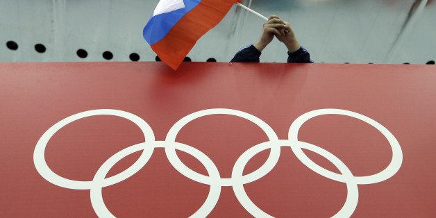 FILE - In this Feb. 18, 2014, file photo, a Russian skating fan holds the country's national flag over the Olympic rings before the start of the men's 10,000-meter speedskating race at Adler Arena Skating Center during the 2014 Winter Olympics in Sochi, Russia. On Monday, July 18, 2016 WADA investigator Richard McLaren confirmed claims of state-run doping in Russia. (AP Photo/David J. Phillip, File)