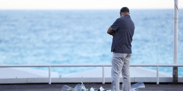 A man passes a make-shift memorial for victims of the deadly Bastille Day attack on July 16, 2016 in Nice.The Islamic State group claimed responsibility for the truck attack that killed 84 people in Nice on France's national holiday, a news service affiliated with the jihadists said on July 16. Tunisian Mohamed Lahouaiej-Bouhlel, 31, smashed a 19-tonne truck into a packed crowd of people in the Riviera city celebrating Bastille Day -- France's national day. / AFP / Valery HACHE (Photo cre