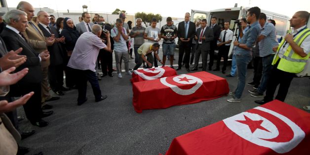 Tahar Mejri (back C) reacts as he stands in front of the flag-draped coffins of his four-year-old son (back) and wife Olfa Bent Souayah Khalfallah (C), who died in the Nice attack, after they arrived, along with the coffin of another victim Bilel Labbaoui, at the airport of Tunis-Carthage on July 19, 2016. / AFP / FETHI BELAID (Photo credit should read FETHI BELAID/AFP/Getty Images)