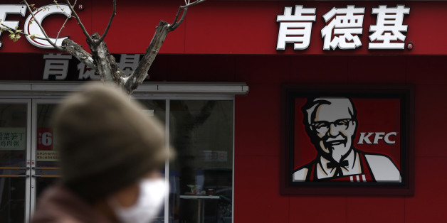 A woman, wearing a mask, rides past a KFC restaurant in Shanghai April 11, 2013. Yum Brands Inc, the biggest foreign fast-food chain operator in China, is in danger of breaking its 11-year streak of double-digit profit growth as it scrambles to deal with food scares and bird flu in its most lucrative market. The U.S.-listed firm, the world's largest restaurant company by number of outlets, said in a filing Wednesday that the latest deadly avian flu outbreak would have a "significant, negative im
