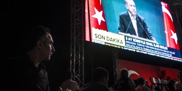 ISTANBUL, TURKEY - JULY 21: People holding Turkish flags watch and listen to Turkish President Recep Tayyip Erdogan on TV as Erdogan delivers a speech during a press conference after the National Security Council and Cabinet meetings, at Taksim Square in Istanbul, Turkey on July 21, 2016. (Photo by Arif Hudaverdi Yaman/Anadolu Agency/Getty Images)