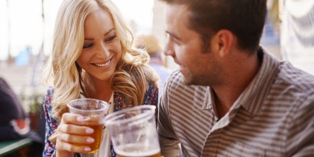 romantic couple drinking beer in plastic cups at outdoor bar with lens flare