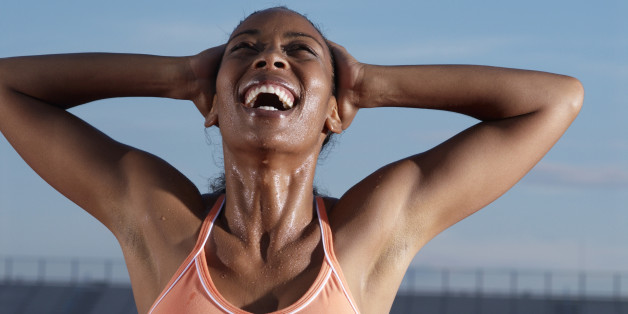 Young female athlete with hands behind head laughing