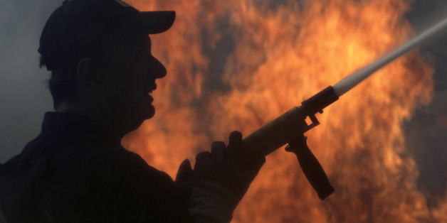A fireman fights a forest fire in the Politia suburb north of Athens August 16, 2007. The fire fanned by gale-force winds swept across the northern Athens suburbs, torching dozens of homes and vehicles and forcing many residents to flee. REUTERS/Yiorgos Karahalis (GREECE)