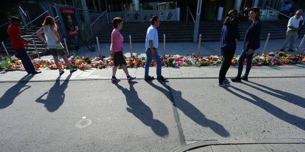 Picture taken on July 24, 2016 shows people standing at a memorial of candles and flowers laid down in front of the Olympia Einkaufszentrum shopping centre in Munich, southern Germany, where an 18-year-old German-Iranian student run amok.
Europe reacted in shock to the third attack on the continent in just over a week, after David Ali Sonboly went on a shooting spree at a shopping centre on July 22, 2016 in what appears to have been a premeditated attack, before turning the gun on himself. / AFP / dpa / Karl-Josef Hildenbrand / Germany OUT (Photo credit should read KARL-JOSEF HILDENBRAND/AFP/Getty Images)