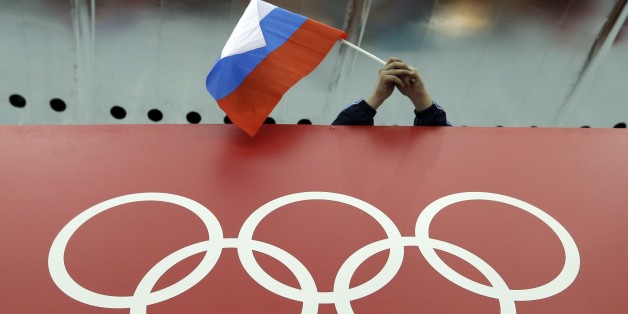 FILE - In this Feb. 18, 2014 file photo, a Russian skating fan holds the country's national flag over the Olympic rings before the start of the men's 10,000-meter speedskating race at Adler Arena Skating Center during the 2014 Winter Olympics in Sochi, Russia. The IOC's ruling 15-member executive board will meet Sunday, July 24, 2016 via teleconference to weigh the unprecedented step of excluding Russia as a whole from the 2016 Rio Olympic Games because of systematic, state-sponsored cheating. (AP Photo/David J. Phillip, file)