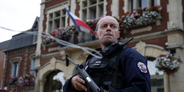 A policeman secures a position in front of the city hall after two assailants had taken five people hostage in the church at Saint-Etienne-du -Rouvray near Rouen in Normandy, France, July 26, 2016. Two attackers killed a priest with a blade and seriously wounded another hostage in a church in northern France on Tuesday before being shot dead by French police. REUTERS/Pascal Rossignol