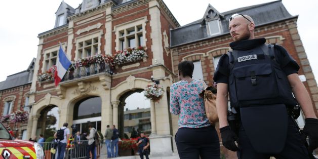 A French police officer stands guard by Saint-Etienne-du-Rouvray's city hall following a hostage-taking at a church in Saint-Etienne-du-Rouvray, northern France, on July 26, 2016 that left the priest dead.A priest was killed on July 26 when men armed with knives seized hostages at a church near the northern French city of Rouen, a police source said. Police said they killed two hostage-takers in the attack in the Normandy town of Saint-Etienne-du-Rouvray, 125 kilometres (77 miles) north of Paris