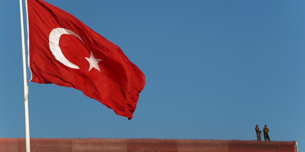 Police officers stand on a building roof overlooking a 'Republic and Democracy Rally' at Taksim square in central Istanbul, Sunday, July 24, 2016. Thousands of supporters of Turkey's main opposition group and some ruling party members rallied in Istanbul to denounce a July 15 coup attempt, a rare show of political unity that belied opposition unease over President Recep Tayyip Erdogan's crackdown since the failed uprising. (AP Photo/Petros Karadjias)