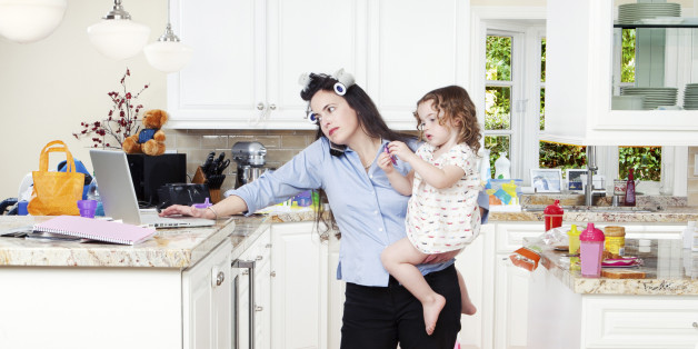 Frustrated mother using laptop and caring for children