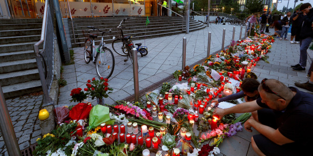 People light candles beside flowers laid in front of the Olympia shopping mall, where yesterday's shooting rampage started, in Munich, Germany July 23, 2016. REUTERS/Arnd Wiegmann