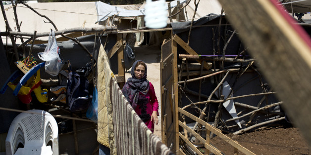 A Syrian woman enters the makeshift courtyard of her family's tent at Ritsona refugee camp north of Athens, which hosts more than 600 refugees and migrants, on Thursday, July 14, 2016. Over 57,000 migrants and refugees remain stranded in Greece following European border closures. The European Union is pressing member states to speed up implementation of its refugee settlement scheme, amid delays in negotiations with Turkey for visa-free travel _ promised by Brussels as part of a deal to limit migrant travel to Europe. (AP Photo/Petros Giannakouris)