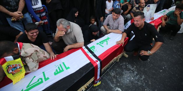 Iraqis mourn next to empty coffins at the site of the explosion in Baghdad's Karrada shopping district during a symbolic funeral on July 10, 2016 for the victims of the attack.In what was one of the deadliest attacks ever to hit Iraq, a suicide bomber blew up a minibus packed with explosives in a Baghdad shopping district teeming with people ahead of the Eid al-Fitr holiday, sparking widespread anger against the government. / AFP / AHMAD AL-RUBAYE (Photo credit should read AHMAD AL-RUBAYE