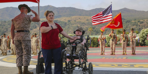 Wyatt Gillette, 8, front right, visits Camp Pendleton, Calif., Saturday, July 30, 2016, with his mother Felicia, front center, as his father, Marine Staff Sgt. Jeremiah Gillette salutes during a ceremony where the young Gillette received an award to become an honorary Marine. Gillette, who had the genetic disease Aicardi-Goutieres syndrome, which causes seizures and kidney failure, died Sunday, July 31, 2016. (Lance Cpl. Angelica Annastas/U.S. Marine Corps via AP)