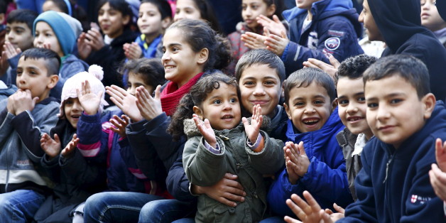 Migrant children react on the arrival of a volunteer dressed as Father Christmas prior to a Christmas gathering, organized by local relief organization "Die Johanniter", with christmas presents for the children at the former US army barracks used as a refugee camp in Hanau, Germany, December 24, 2015. REUTERS/Kai Pfaffenbach