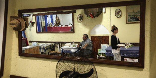 In this photo taken Sept. 30, 2015, a waitress carries dishes inside a restaurant on the Greek Aegean island of Naxos. For decades, Greeceâs Aegean islands enjoyed a value added tax rate 30 percent lower than the rest of the country, to offset increased transportation costs and prevent their dwindling permanent populations from deserting them altogether, but now the islands are losing that benefit as part of creditor-demanded reforms for Greece's third international bailout. (AP Photo/Yorgos Karahalis)