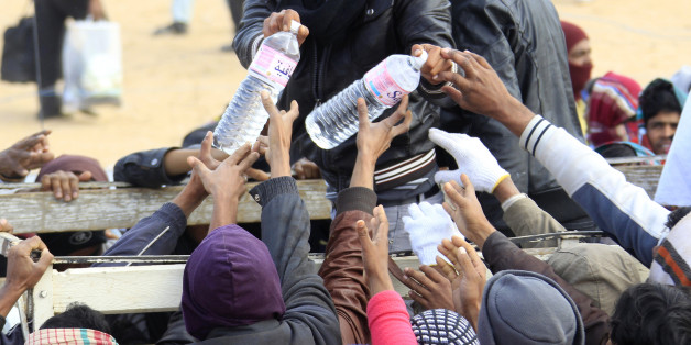 Evacuees receive bottles of water during food distribution at the UNHCR refugee camp near the border crossing of Ras Jdir, after fleeing the violence in Libya March 9, 2011. REUTERS/Pascal Rossignol (TUNISIA - Tags: CIVIL UNREST POLITICS SOCIETY)