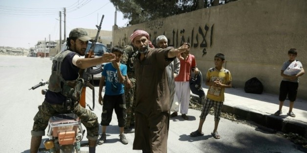 Un membre des Forces démocratiques syriennes (FDS) indique le chemin aux civils fuyant un quartier contrôlé par les jihadistes de l'EI à Minbej, le 7 août 2016