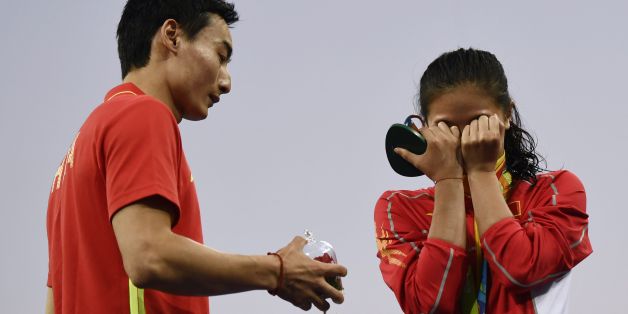 TOPSHOT - Silver medallist China's He Zi (R), reacts she receives a marriage proposal from Chinese diver Qin Kai during the podium ceremony of the Women's diving 3m Springboard Final at the Rio 2016 Olympic Games at the Maria Lenk Aquatics Stadium in Rio de Janeiro on August 14, 2016. / AFP / CHRISTOPHE SIMON (Photo credit should read CHRISTOPHE SIMON/AFP/Getty Images)