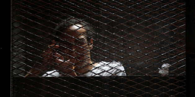 Egyptian photojournalist Mahmoud Abu Zeid, also known as "Shawkan", gestures behind bars in his trial at on the outskirts of Cairo, Egypt May 31, 2016. REUTERS/Amr Abdallah Dalsh