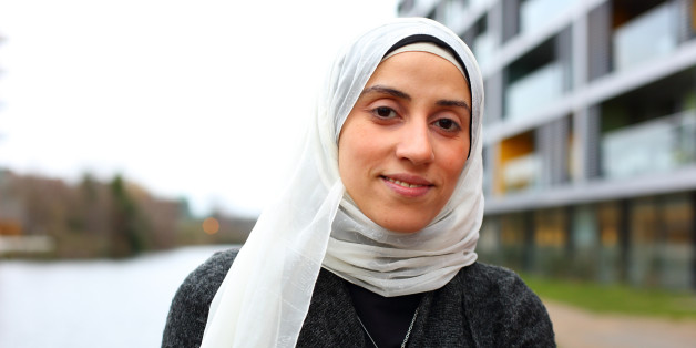 Muslim migrant woman sitting at the river bank in the urban environment