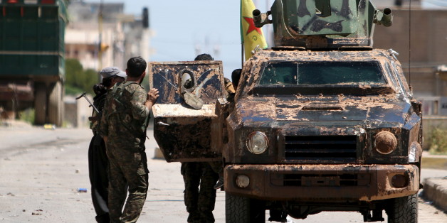 Kurdish fighters from the People's Protection Units (YPG) stand near a military vehilce in the southeast of Qamishli city, Syria, April 22, 2016. REUTERS/Rodi Said