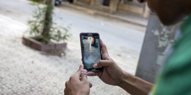 In this Wednesday, July 20, 2016 photo, Egyptian dentist Mark Shehata, 24, holds his smart phone as he uses the "Pokemon Go," mobile phone application on a street in Cairo, Egypt. Abbas Shumman, the deputy sheikh of Egypt's Al-Azhar institute, has warned against the dangers of playing too much of the wildly popular mobile phone application, adding to religious voices that have sometimes been sterner in their critique of the game. (AP Photo/Amr Nabil)