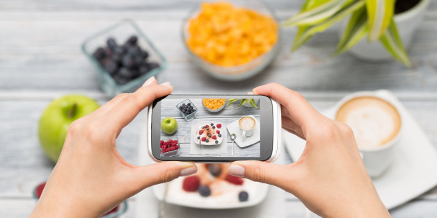 Woman taking a photo of breakfast with smartphone.