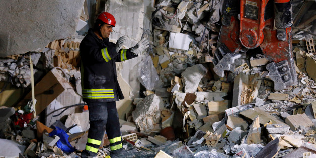 A firefighter works in the night at a collapsed house following an earthquake in Amatrice, central Italy, August 24, 2016.