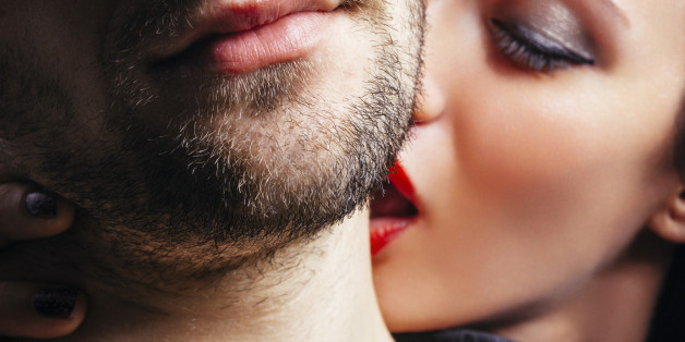 Close up of a women passionately kissing a man on the neck.