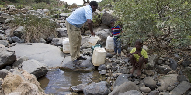 A man and his grandchildren collect water from the Nkuzana River as water to homes has been cut off due to drought near Pongola, northeast of Durban, January 20, 2016. REUTERS/Rogan Ward