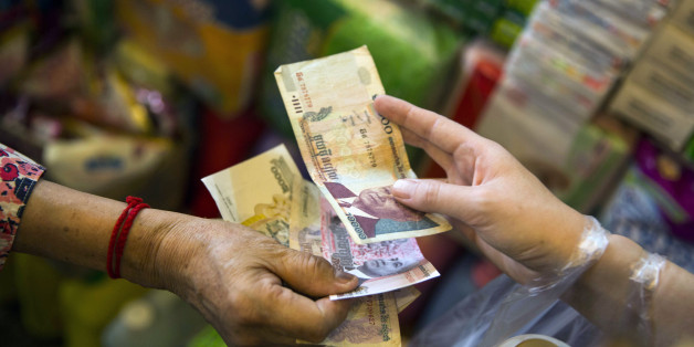 A customer and vendor exchange Cambodian riel banknotes at a market stall in Phnom Penh, Cambodia, on Wednesday, March 2, 2016. By 2030, more than half of 650 million people in Southeast Asia will be under the age of 30, part of an emerging middle class with high rates of consumption. Photographer: Taylor Weidman/Bloomberg via Getty Images