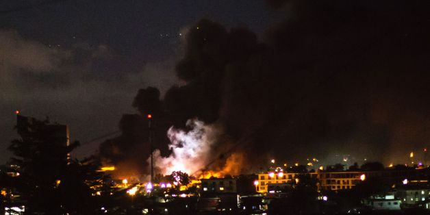 TOPSHOT - The flash of an explosion is pictured amid flames and smoke billowing from the National Assembly building in Libreville after it was set ablaze on August 31, 2016 by demonstrators protesting after Gabon's president Ali Bongo was declared winner of last weekend's contested election. Gabon's national assembly was set ablaze on August 31, 2016 evening by angry protestors who took to the streets after an announcement that President Ali Bongo had been re-elected, witnesses said.'The whole
