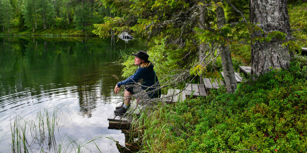 Woman sitting on pier on mountain lake